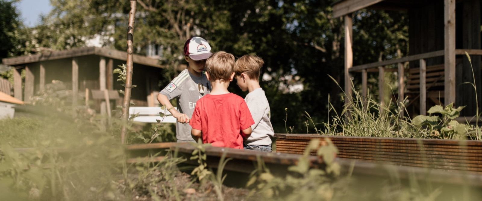 Kinder und ein Betreuer im Garten am Hochbeet