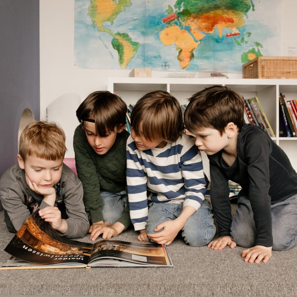 Vier Schulkinder schauen sich gemeinsam ein Buch an