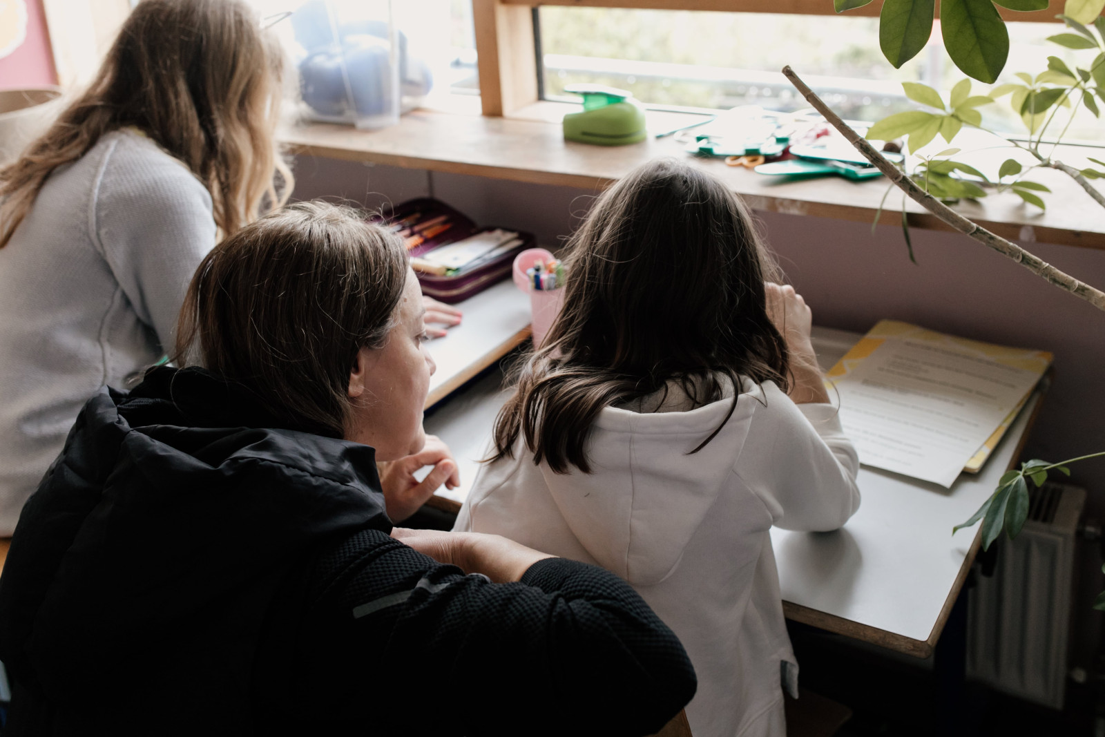 Schulkinder machen mit einer Betreuerin Hausaufgaben