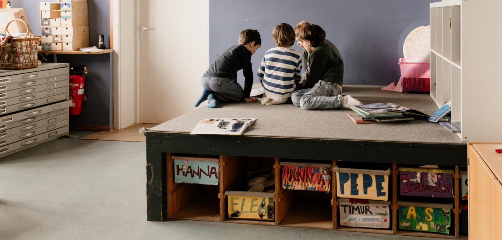 Schulkinder sitzen zusammen auf einem Podest im Hortraum