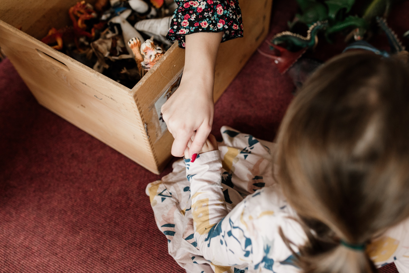Ein Kind holt Spielsachen aus einer Holzkiste