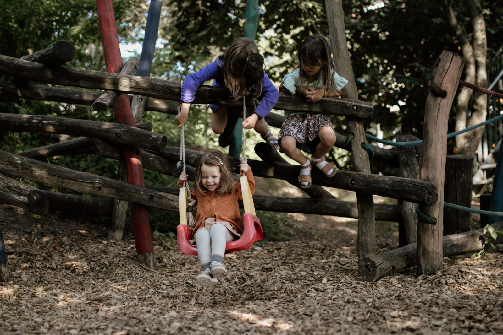 Kinder klettern und schaukeln am Holzklettergerüst im Garten